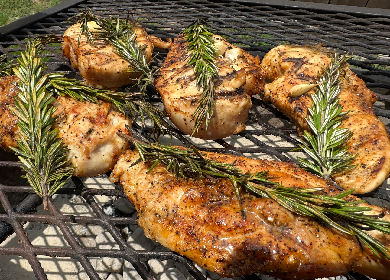 Grilled chicken pieces topped with fresh rosemary leaves